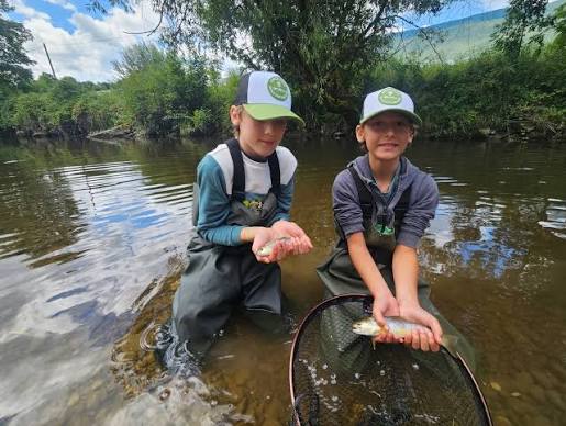 Deux jeunes pêcheurs présentent leurs prises en rivière