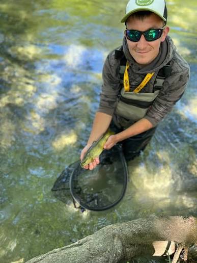 Un pêcheur et sa truite au bord de l’épuisette